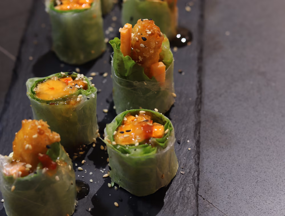 Ensalada Ebi Spring Roll - rollitos de papel de arroz con ensalada y langostino, cortados y emplatados sobre pizarra en Hito